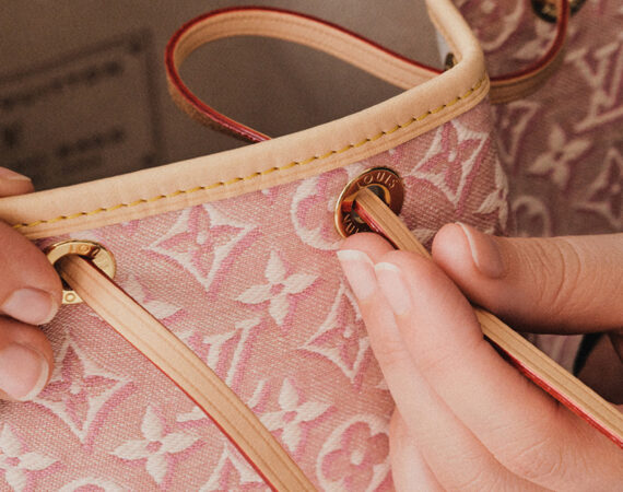 Inserting the loop through the eyelets of the Noe Monogram Embleme