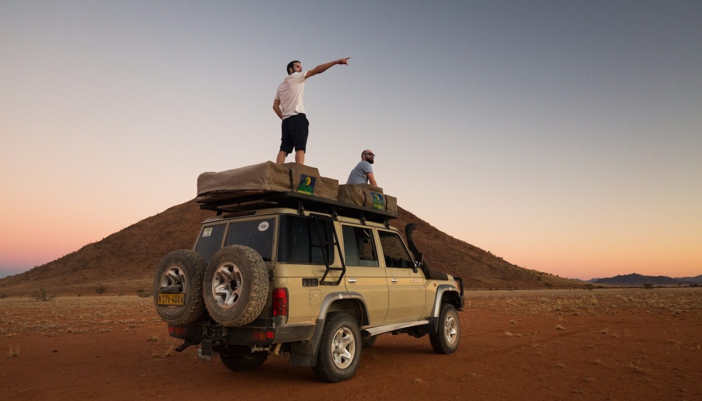 Two men looking at desert from top of car