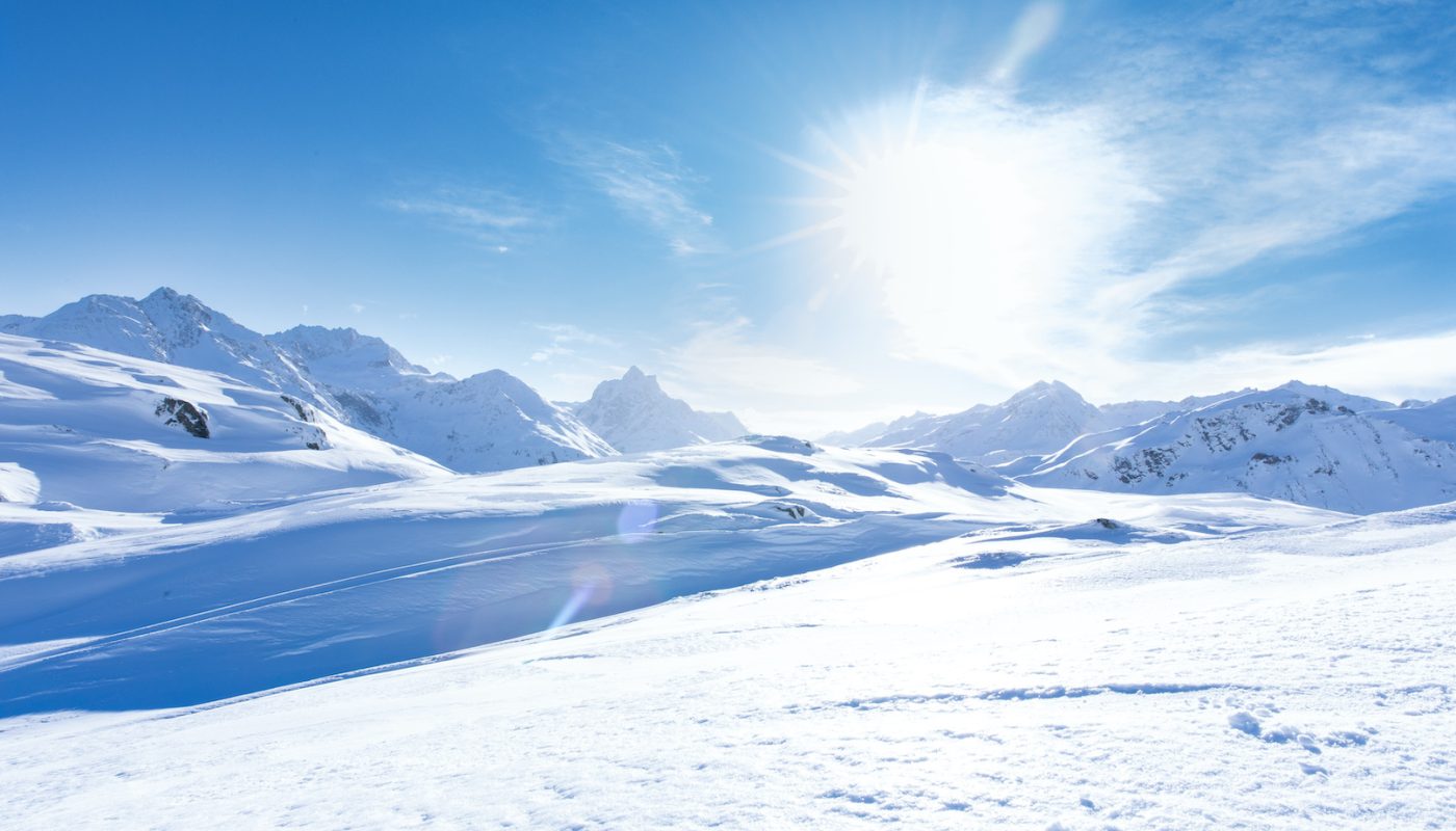 Junge sportliche Frau fährt Ski, macht Winter Sport in einem Winter Paradis. Schnee bedeckte Berge, blauer Himmel und Farbenfroher Ski Anzug